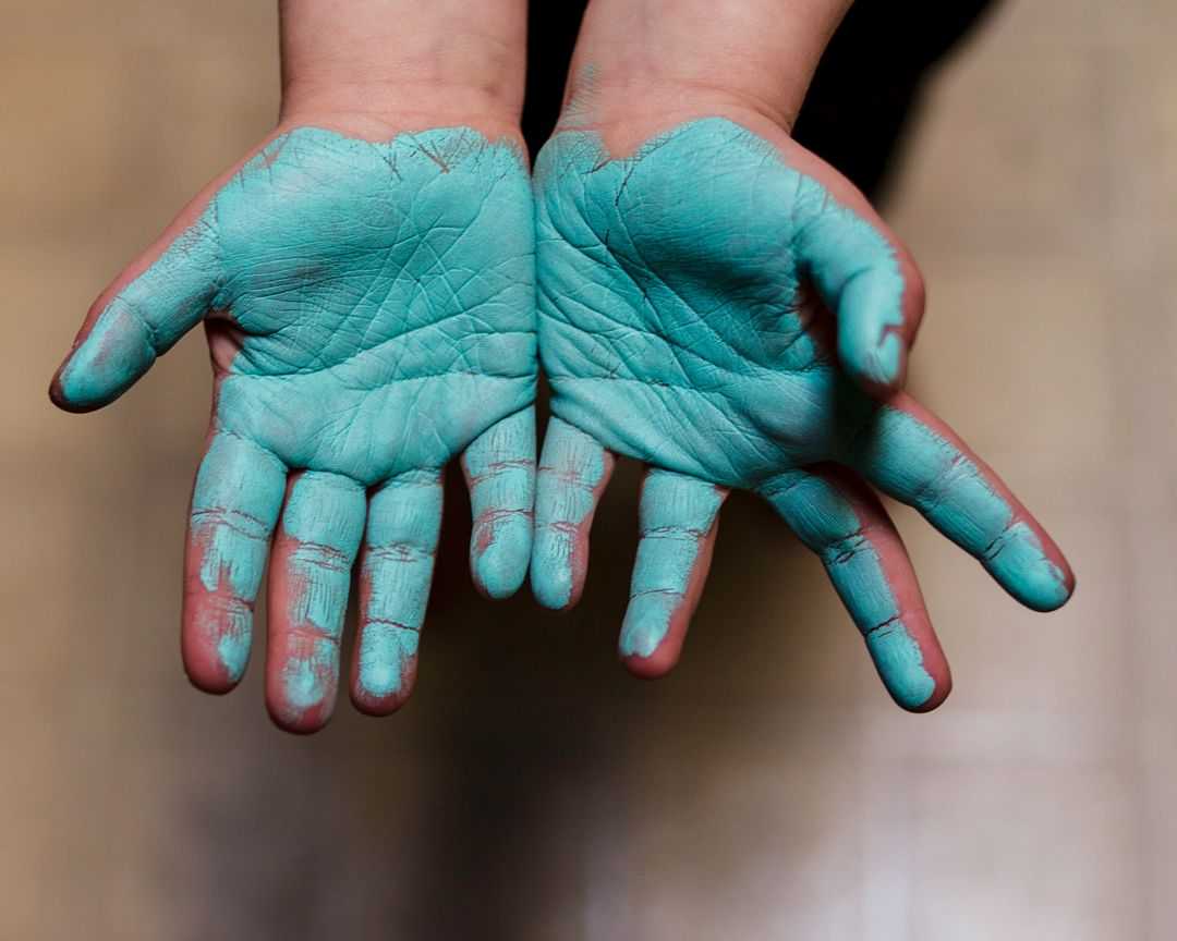 child hands with blue paint