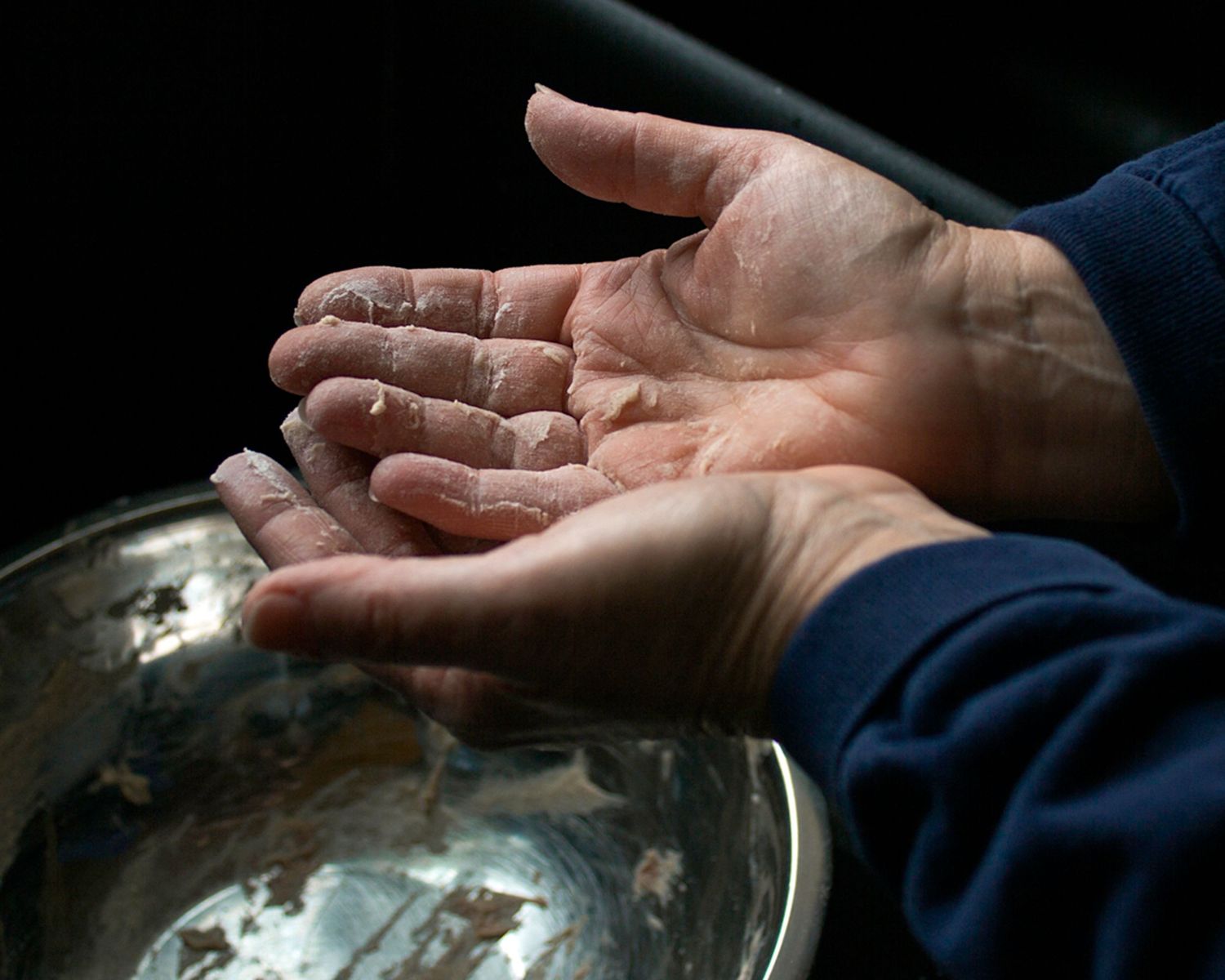 image of hands caked with dough, subject appears to be baking
