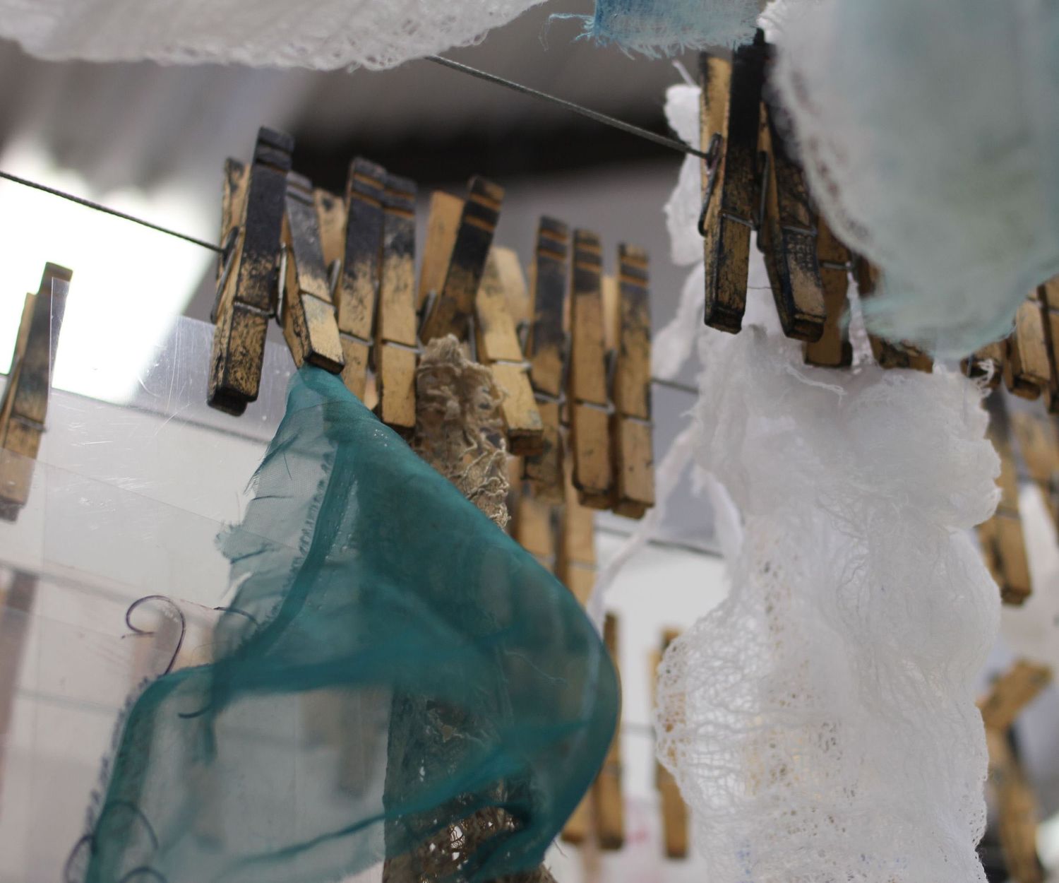 soft focus image of ceiling of artist's studio, clothespins hold various scraps of fabric