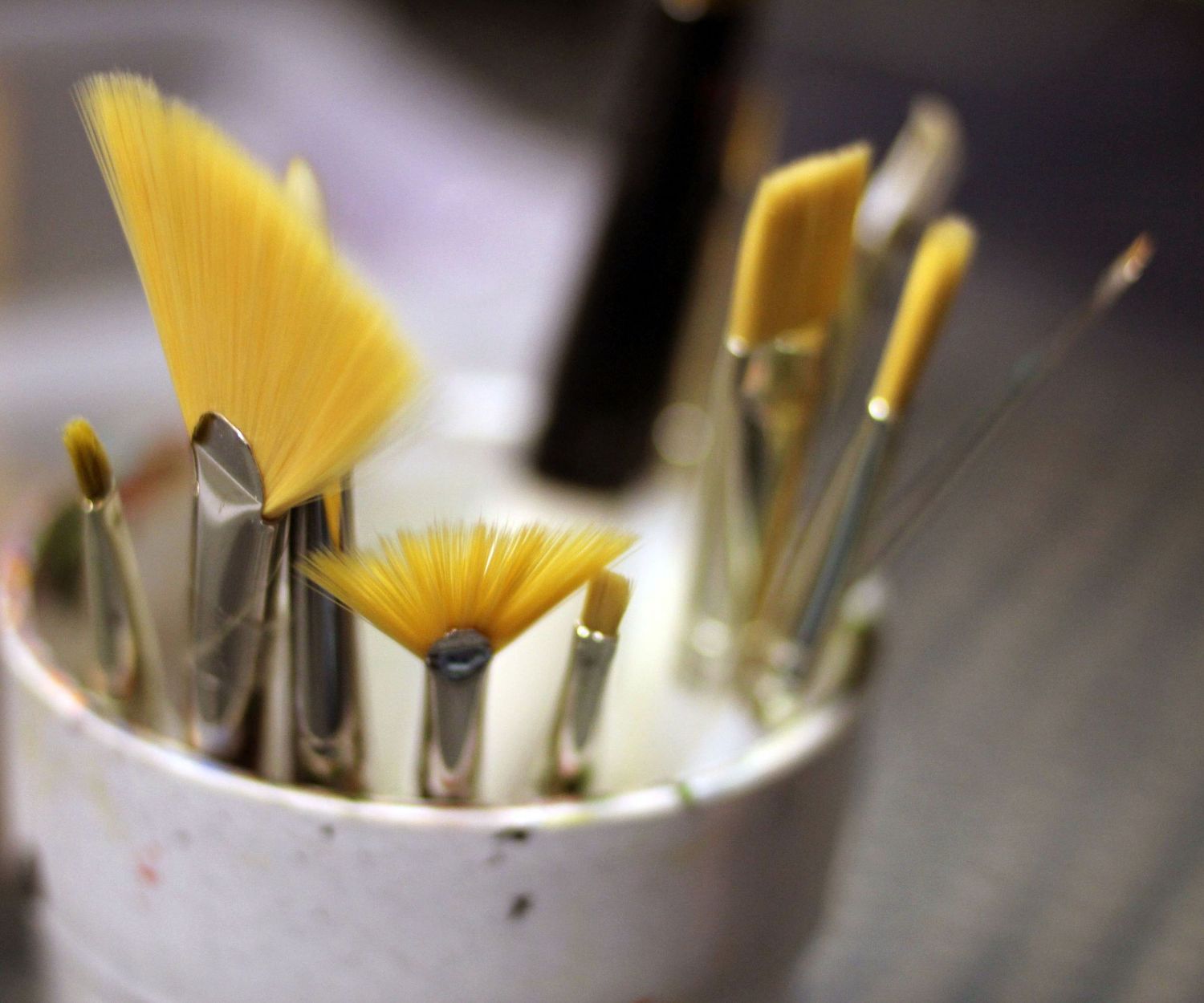 paintbrushes flaring out of jar on soft focus