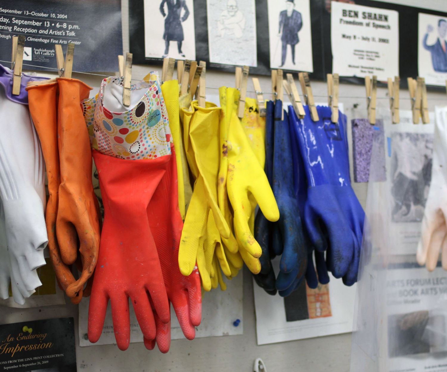 colorful rubber gloves in artist's studio hang from wire