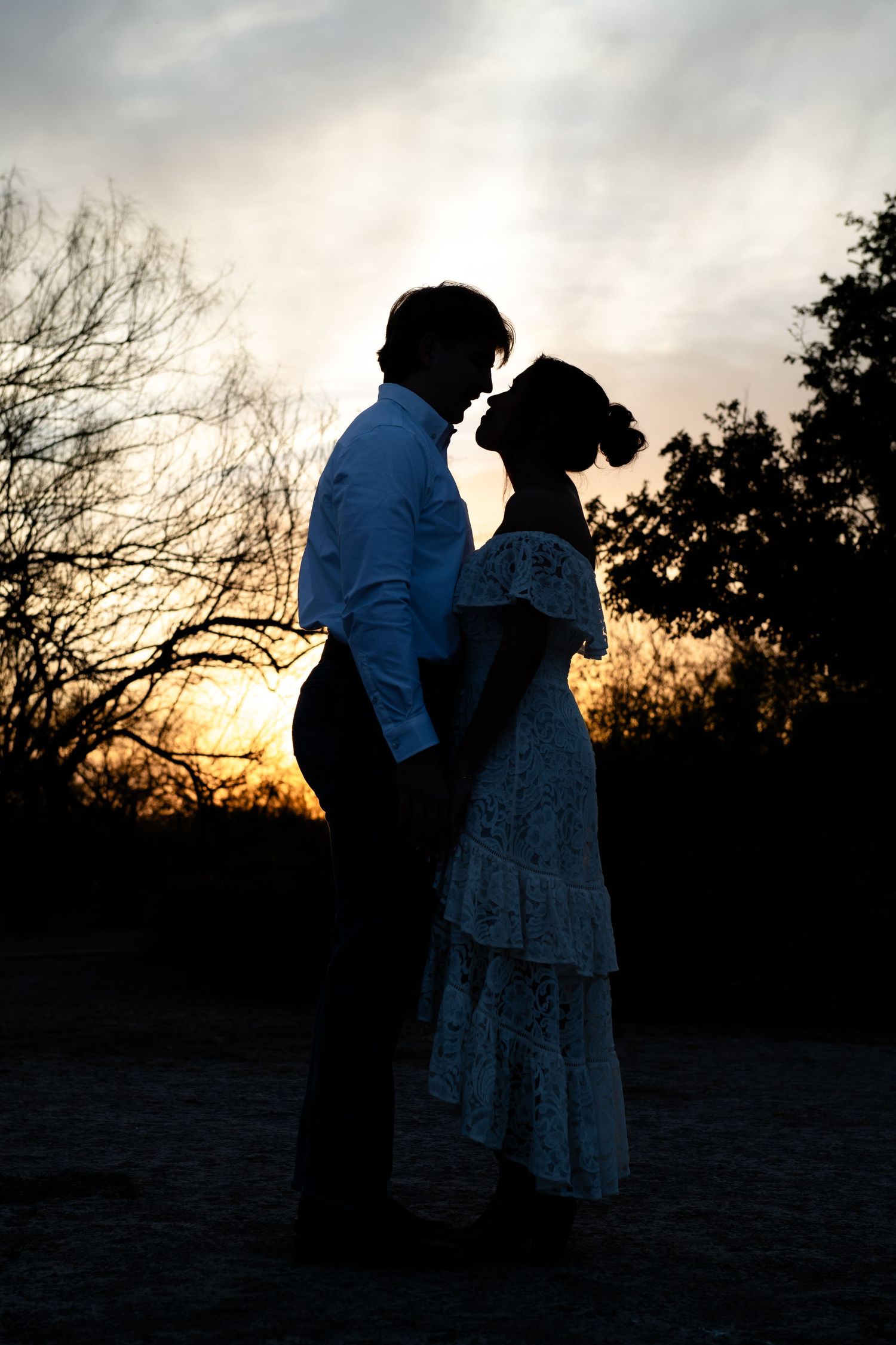 Champagne bottle and two glasses in foreground with dancing couple silhouetted in background.