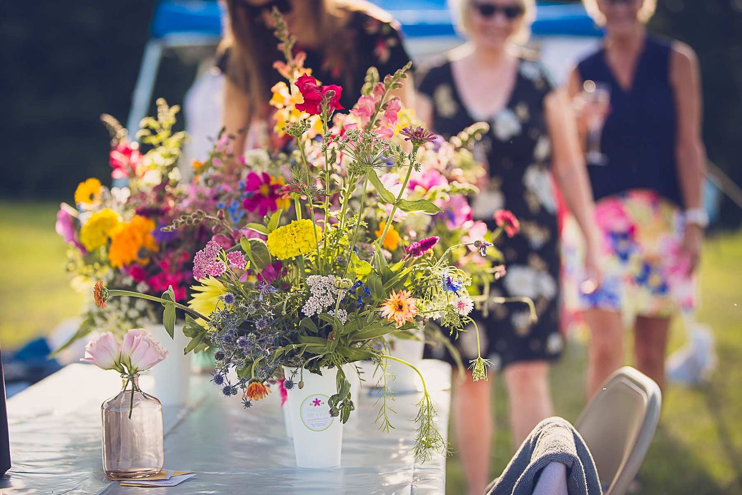 Colorful wildflower arrangements in rustic vases displayed outdoors.