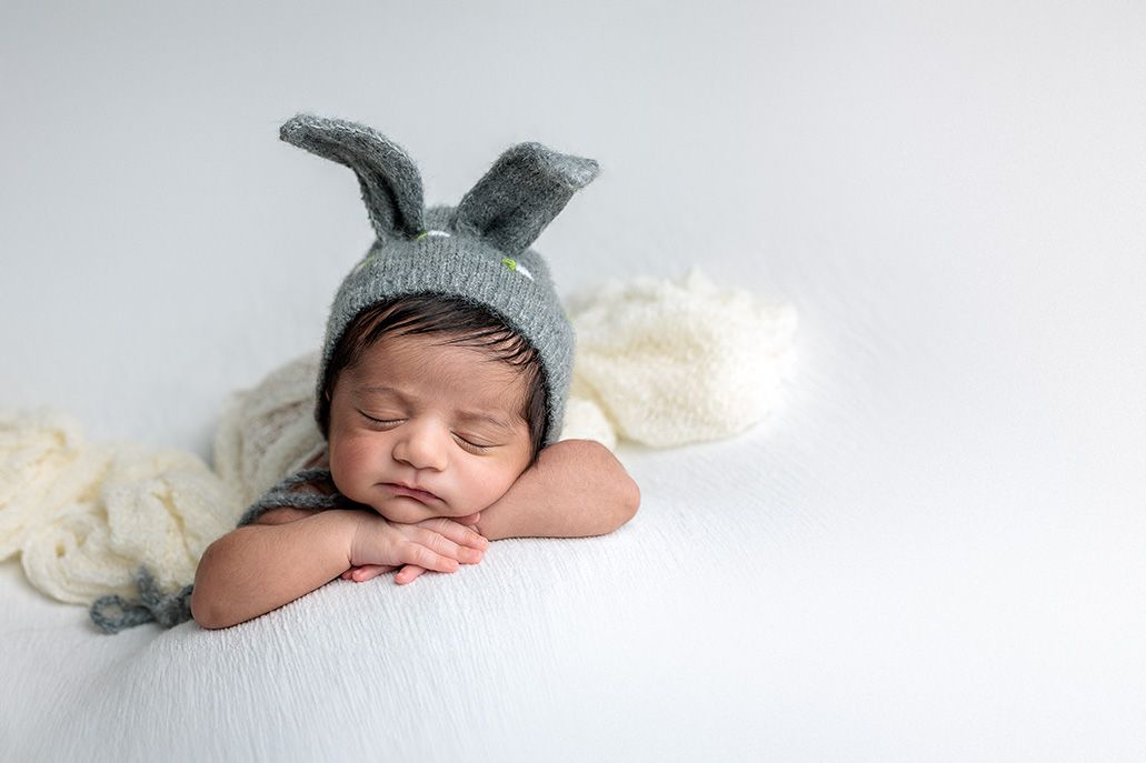 A sleeping baby boy wearing a easter bonnet during a newborn photo session at a photography studio near Austin