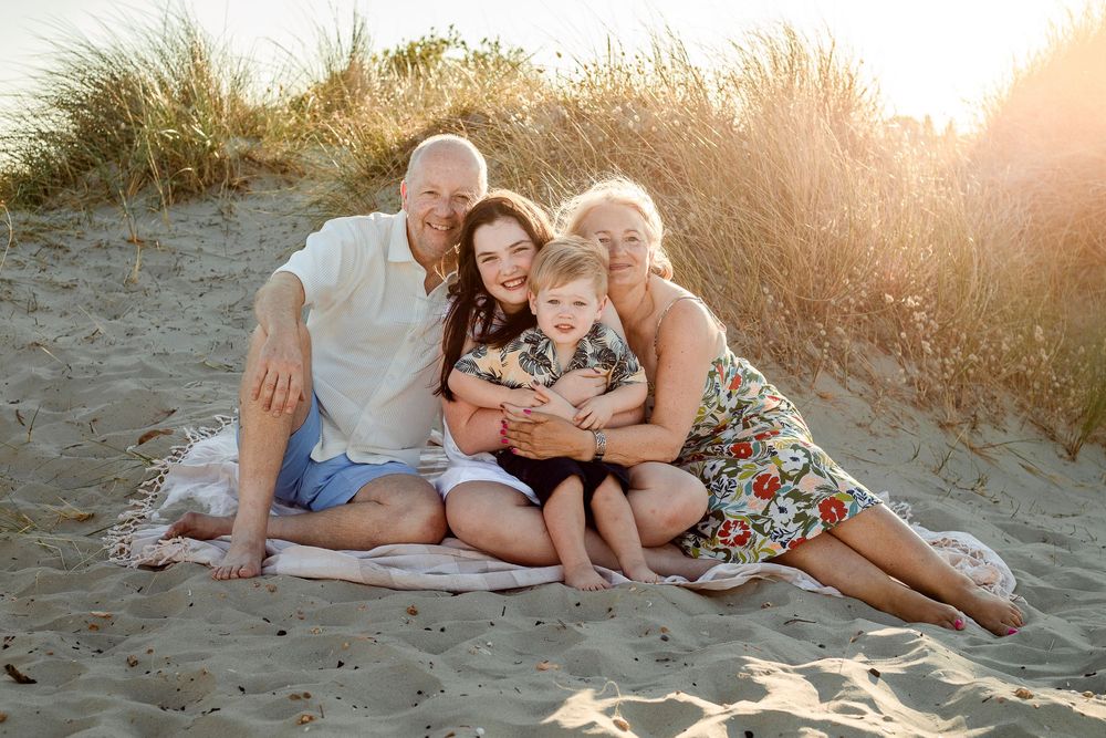 On a beach on Hayling Island, Hampshire, a couple sits in the sand hugging their grand children at Sunset.