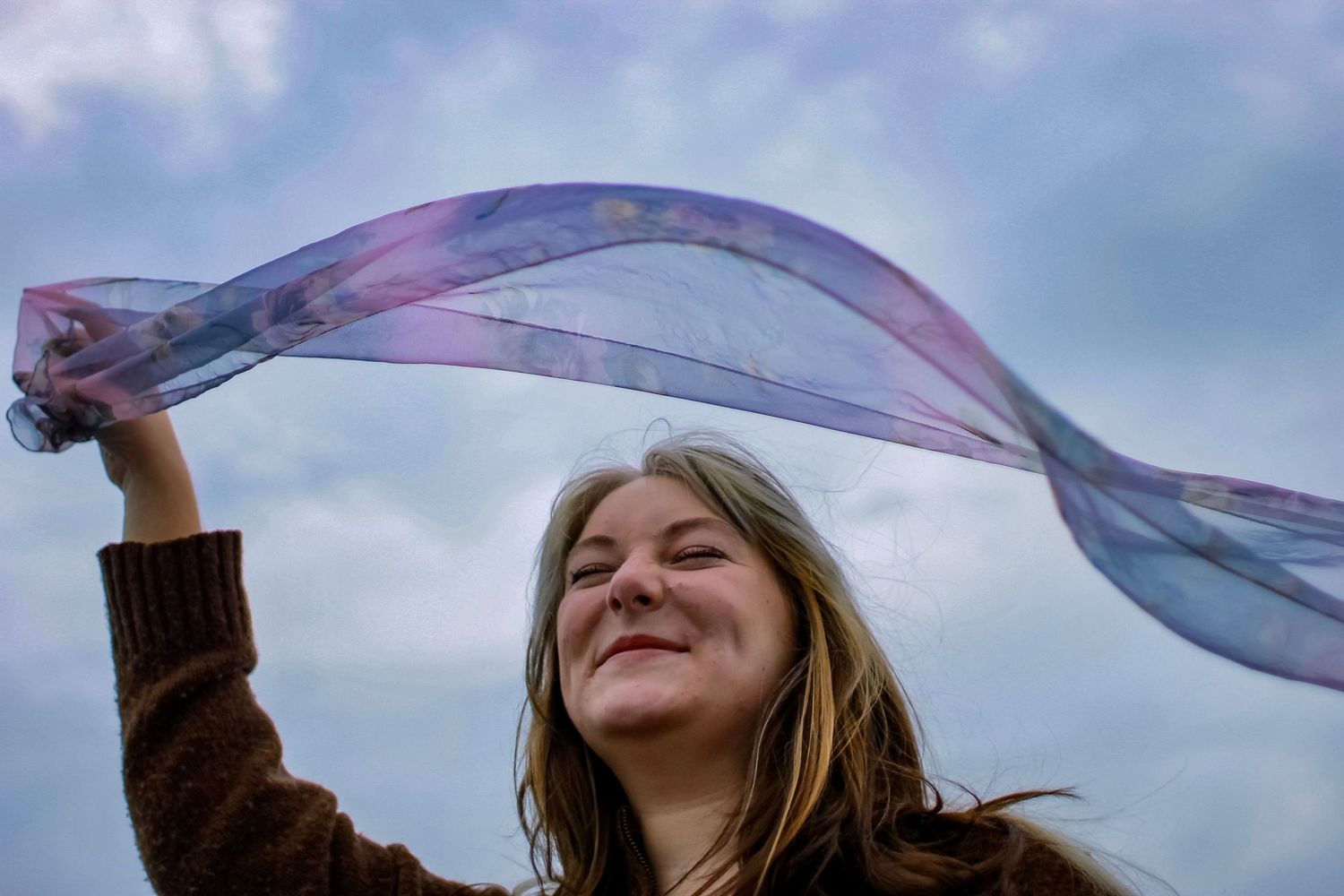 A girl waves a scarf above her head during an editorial photo session