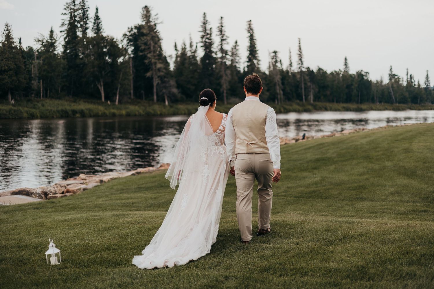 Bride and groom sharing romantic moment by lake with birch trees in background.