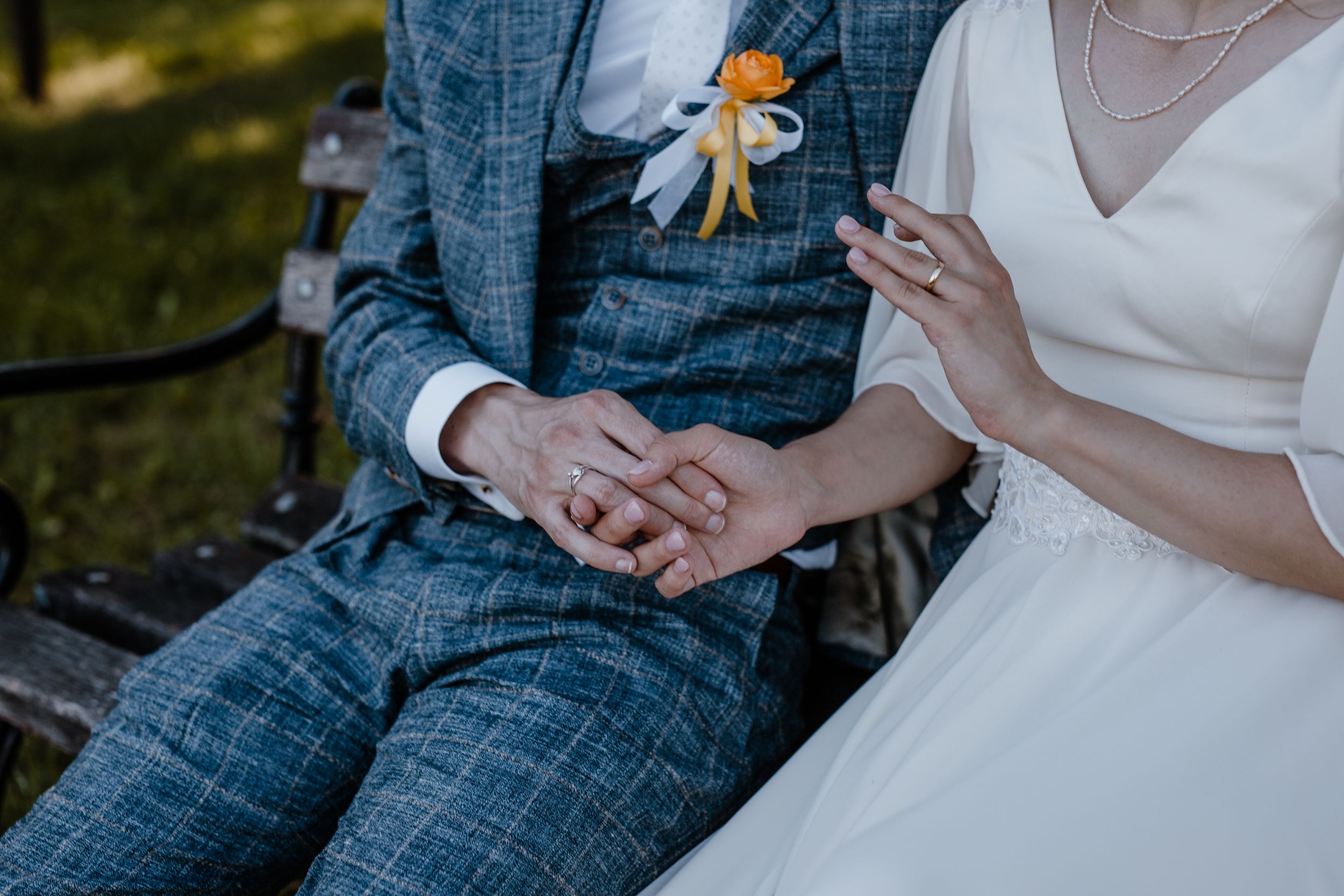 Detalj vjenčane fotografije gdje se mladenci drže za ruku i vidimo njhovo vjenčano prstenje.
