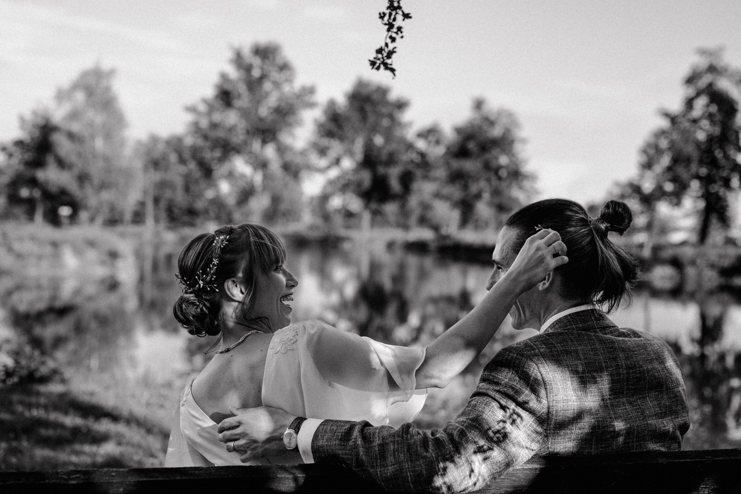 Candid wedding moment of the couple laughing near the water.