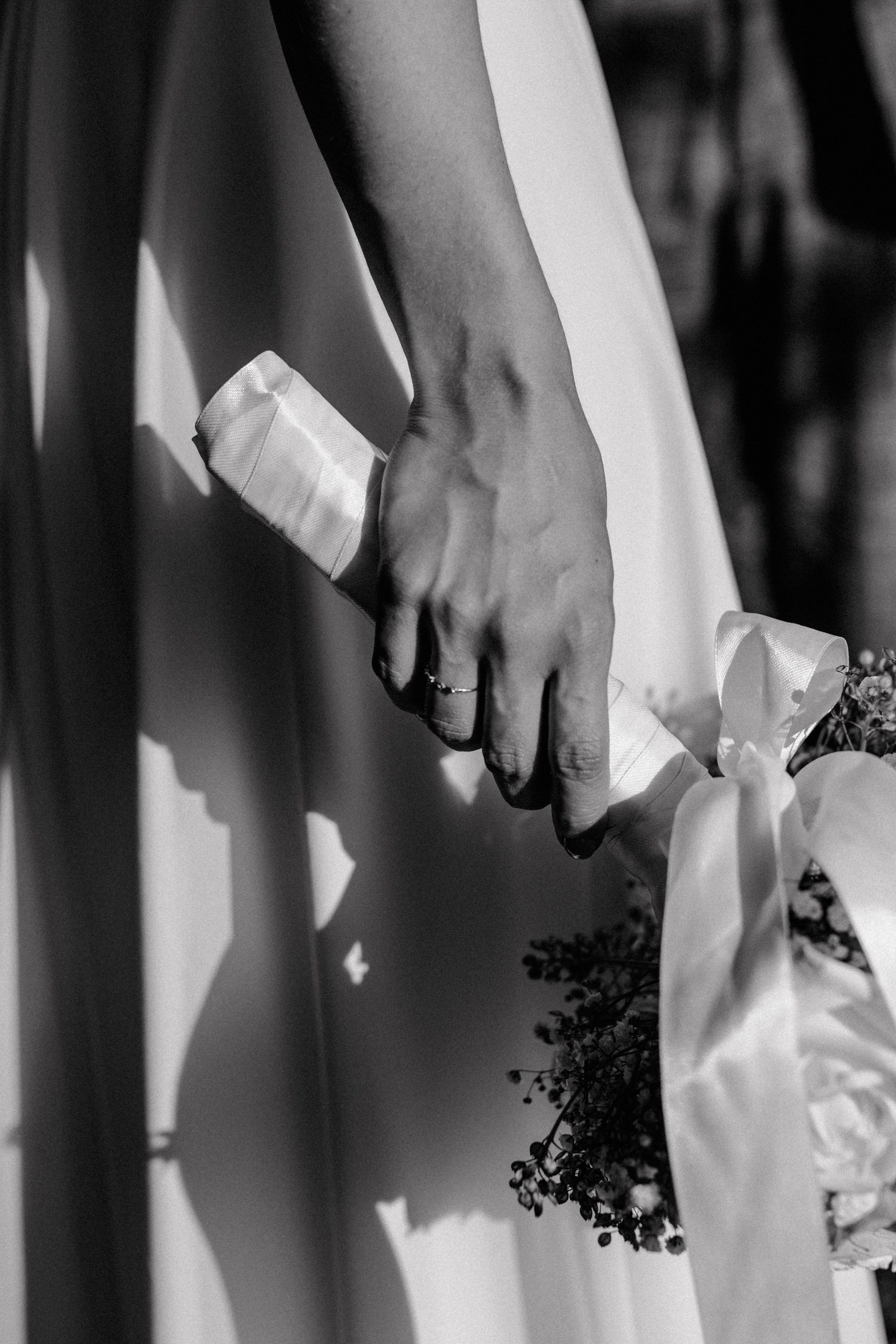 Detalj ruke koja elegantno drži buket prikazano kroz vjenčanu fotografiju.