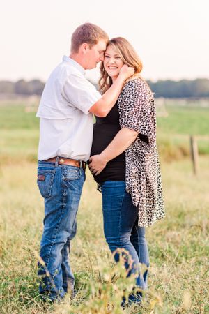 A candid moment between a couple during a casual outdoor maternity photoshoot.