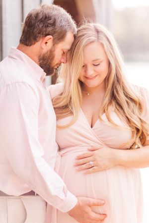 An intimate maternity moment captured in soft lighting with the couple in blush tones.