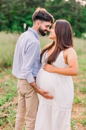 Intimate maternity portrait showing couple's tender moment in natural outdoor setting.