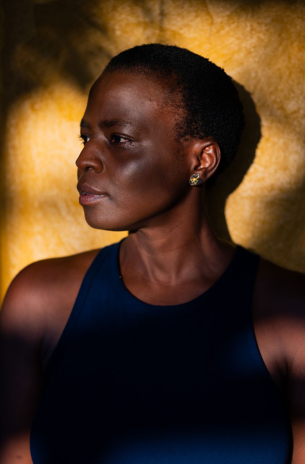 Artistic portrait against golden background highlighting strong features and profile in dramatic lighting.