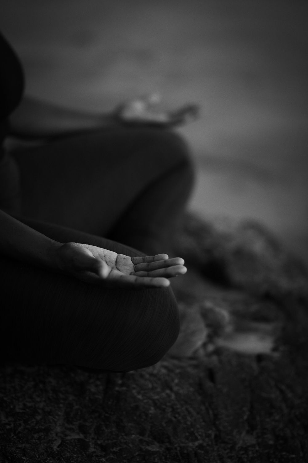 Black and white meditation pose detail showing open palm in peaceful setting.