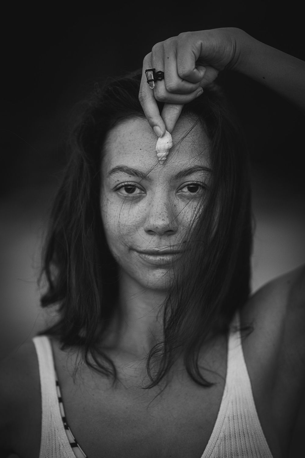 Black and white portrait of woman in white tank top with gentle expression.