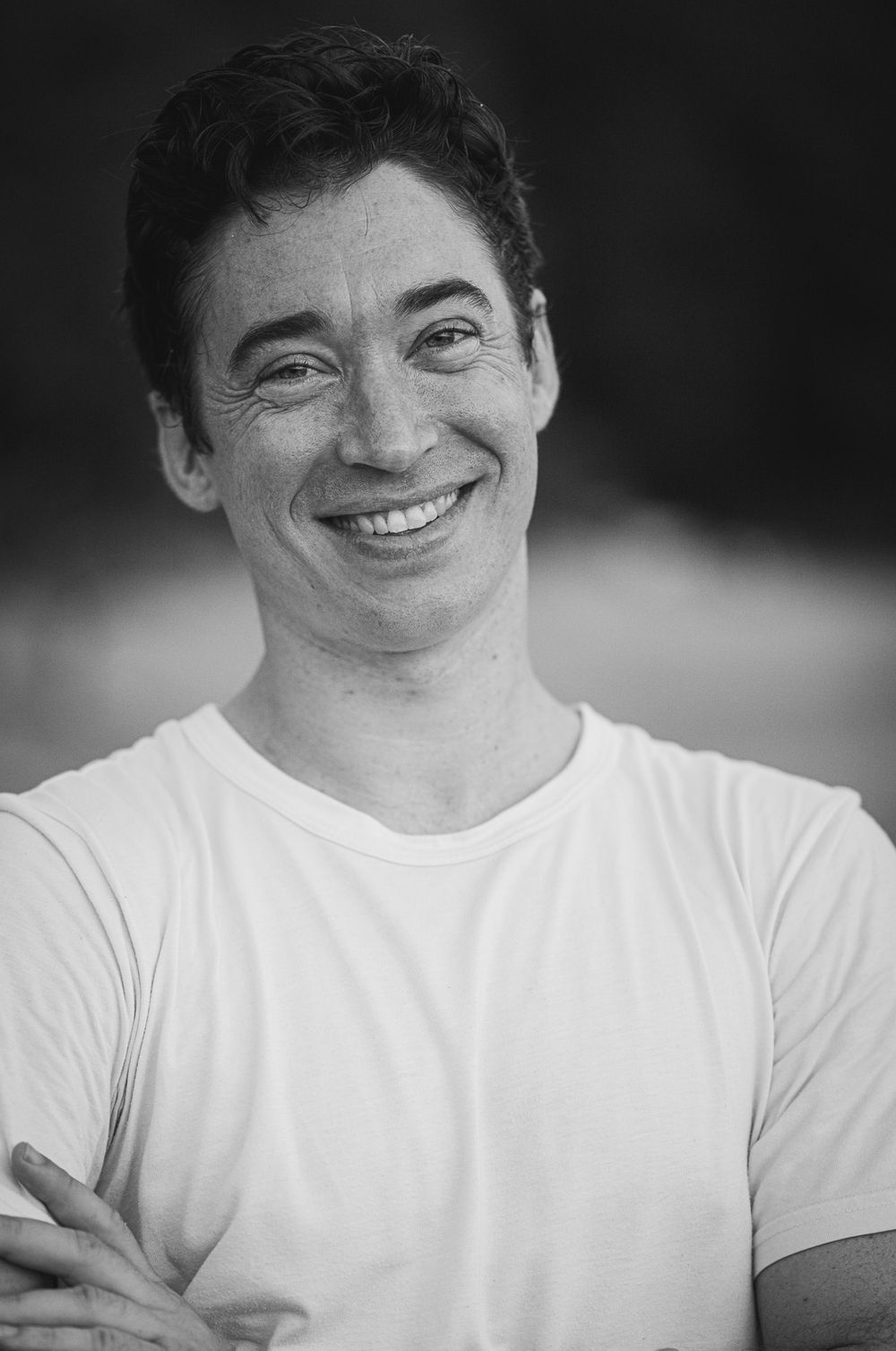 Black and white portrait of person in white t-shirt with warm smile.