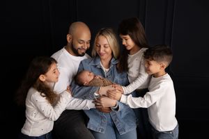 Family portrait session against black background showing tender moments and embraces.