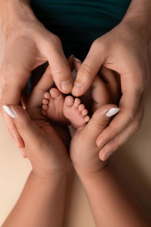 Close-up view of two hands gently touching and intertwining fingers against a neutral background.