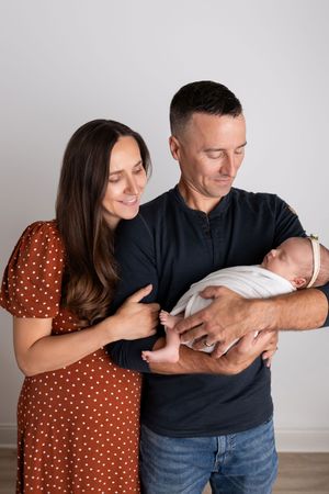 A series of four connected photos showing a couple in casual attire interacting with a baby in a tender moment.