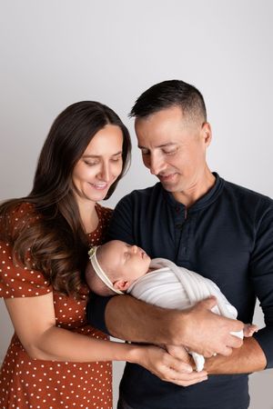 A couple in navy and polka dots share tender moments with their newborn baby in a series of candid studio photos.