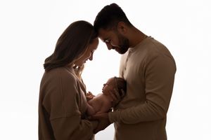 Silhouetted figures embrace tenderly against a light background in an intimate portrait session.