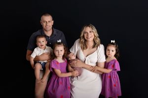A family wearing coordinated black and purple outfits poses together for a series of professional studio portraits.