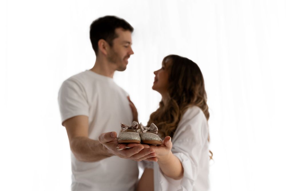 A couple in white outfits holding something together while smiling.