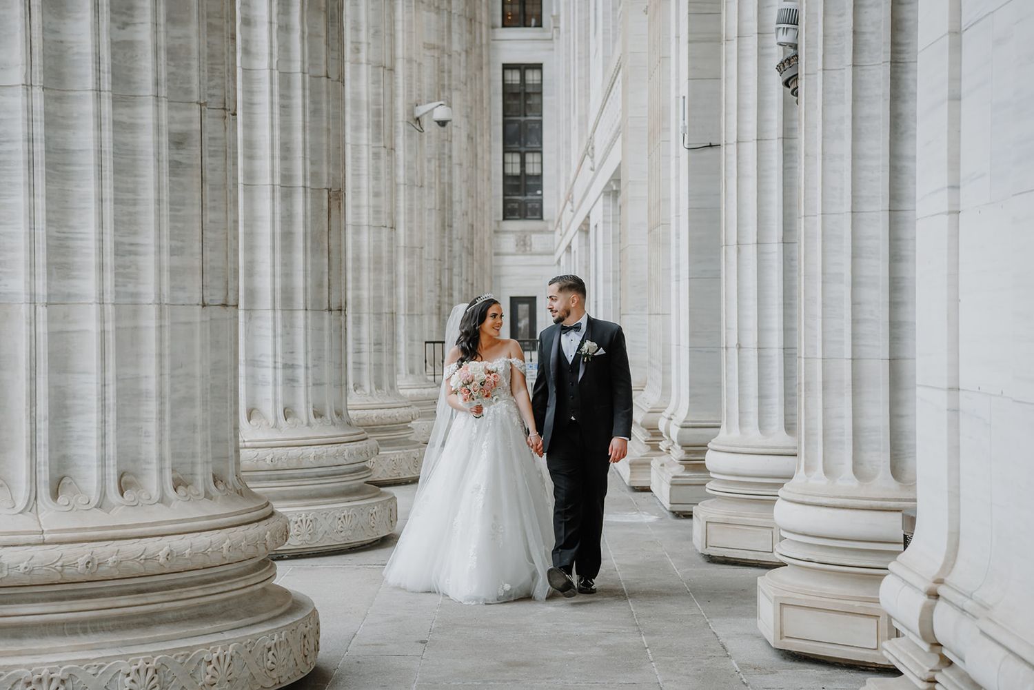 Wedding couple poses in an elegant white colonnade with classical architectural columns in downtown Albany NY