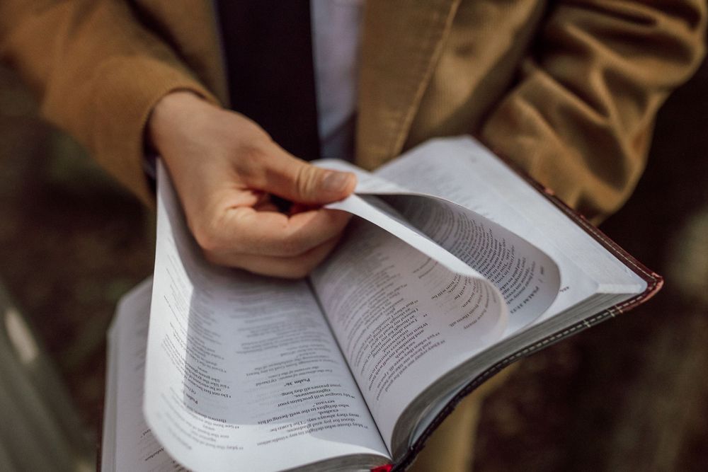 groom reading Bible in forest elopement ceremony in virginia beach, virginia