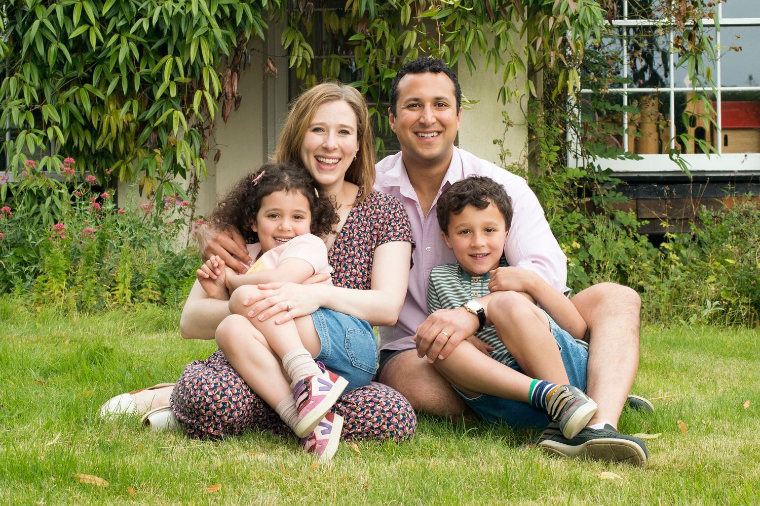 A family enjoys a sunny day sitting on the grass in front of their home, captured during a photoshoot in Buckinghamshire.