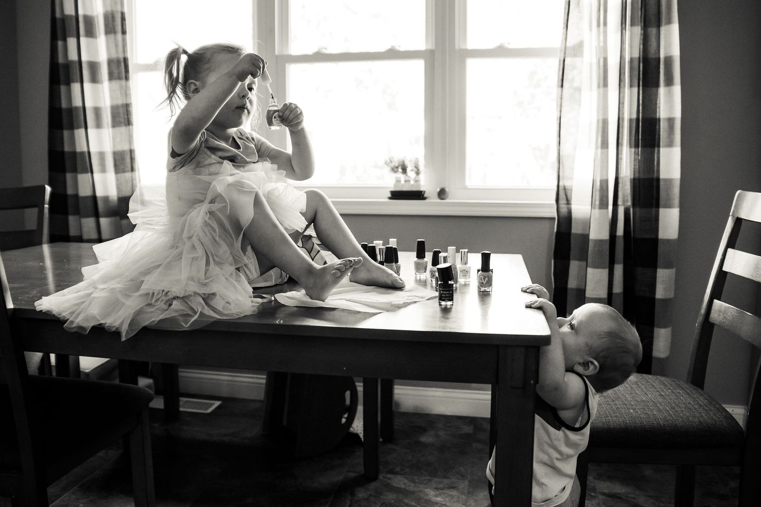 Black and white image of children playing dress up and having tea party.