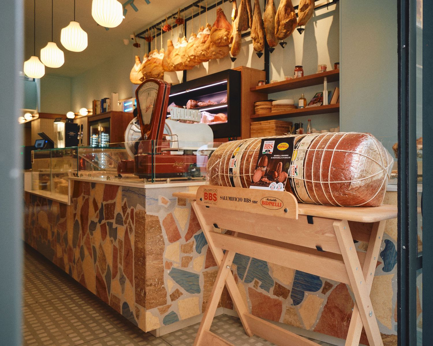 Interior of traditional deli shop with hanging meats and wooden counter display.