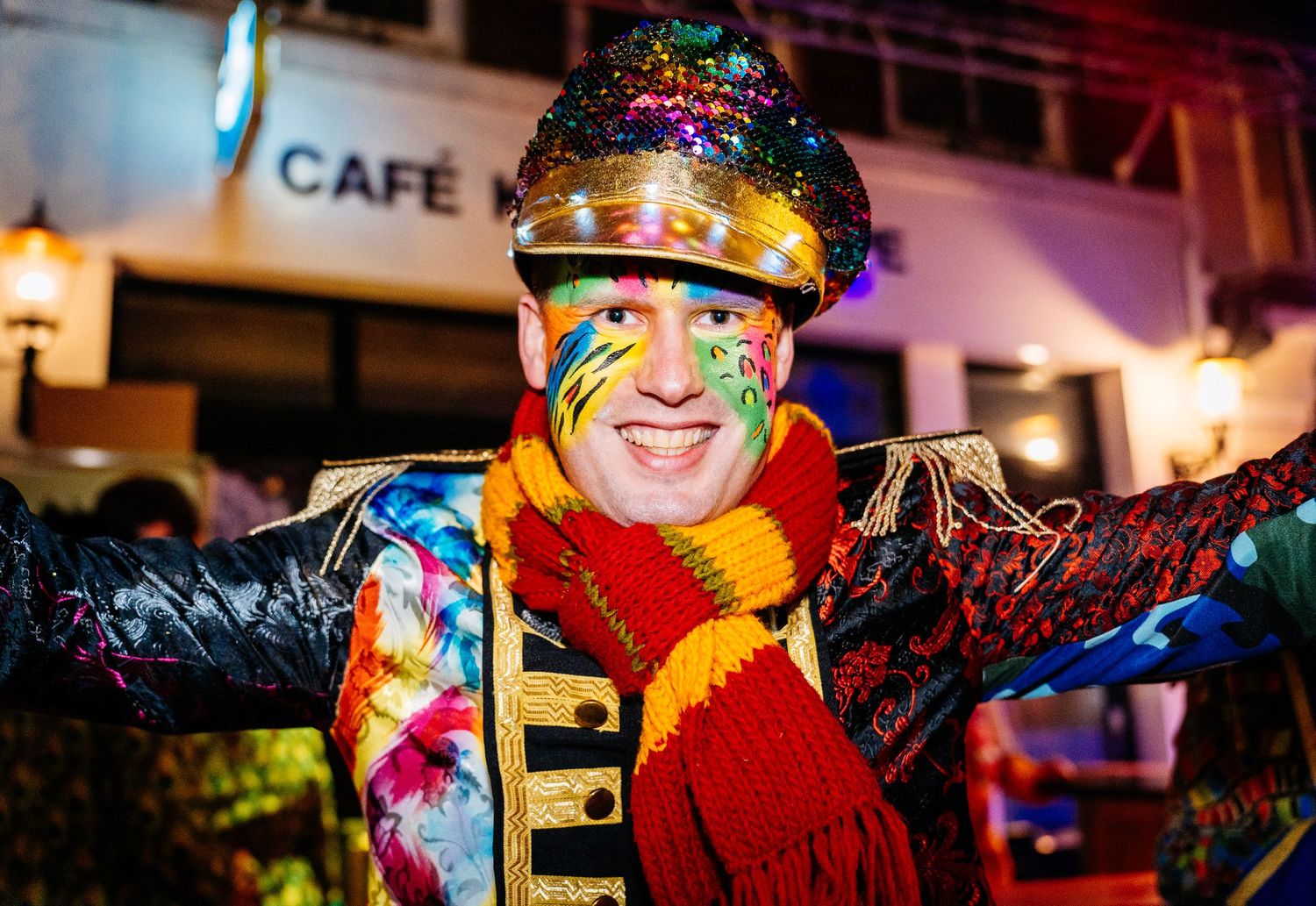 Close-up of a men in a carnival costume dancing energetically in a crowded venue in vibrant pink and purple party lights. vastelaovend venlo