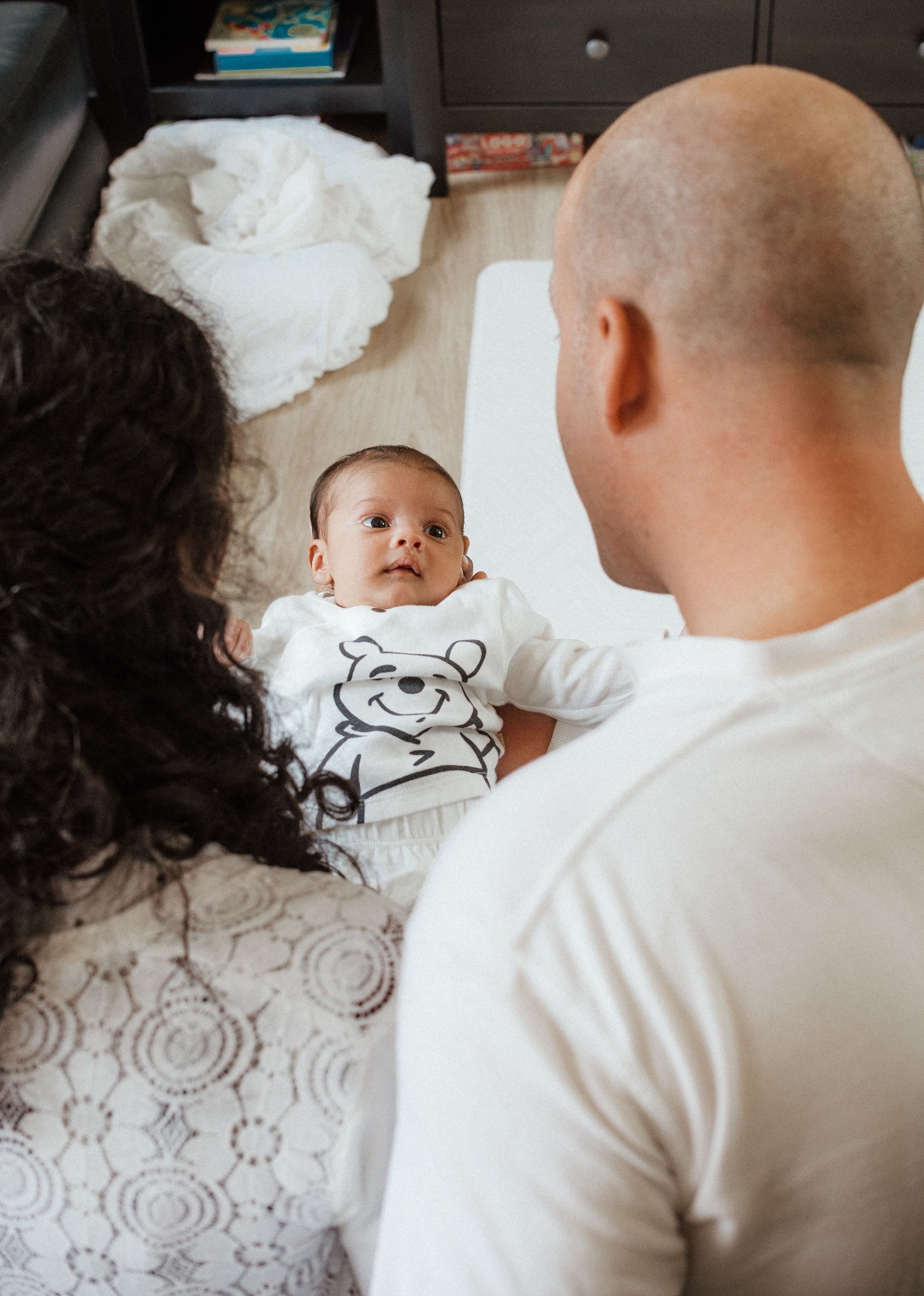 White onesie with teddy bear design laid on patterned fabric.