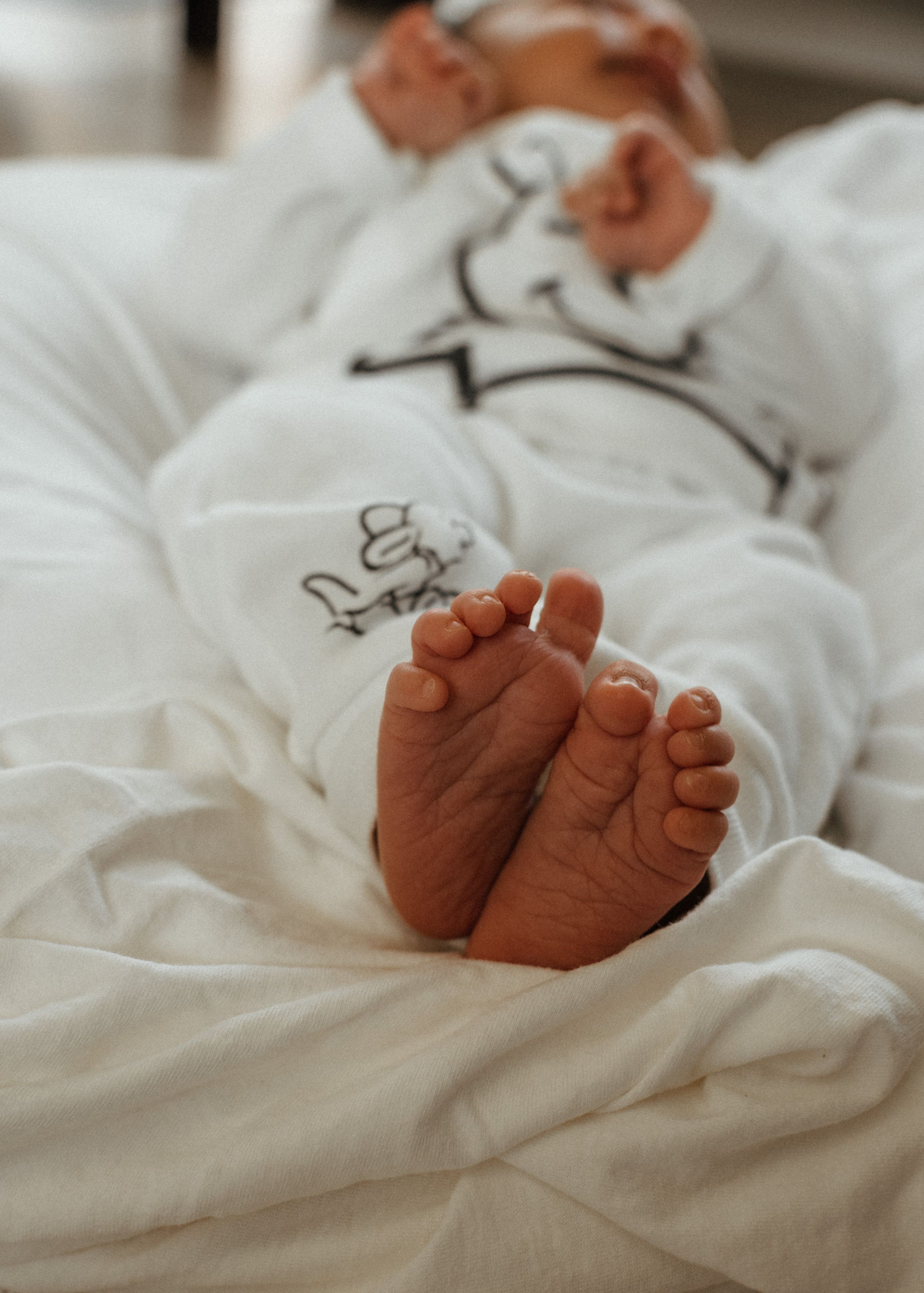 Close-up of tiny baby feet resting on white fabric.
