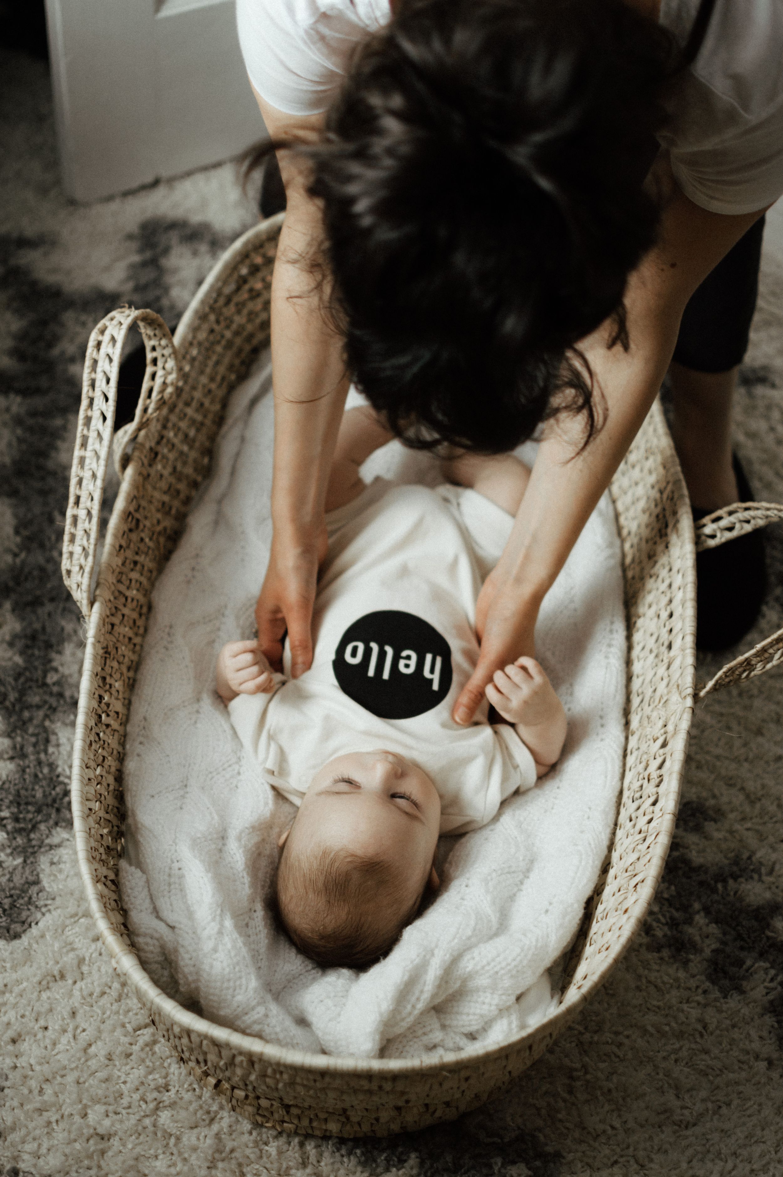 Overhead view of woven basket with soft white blanket and round sign.