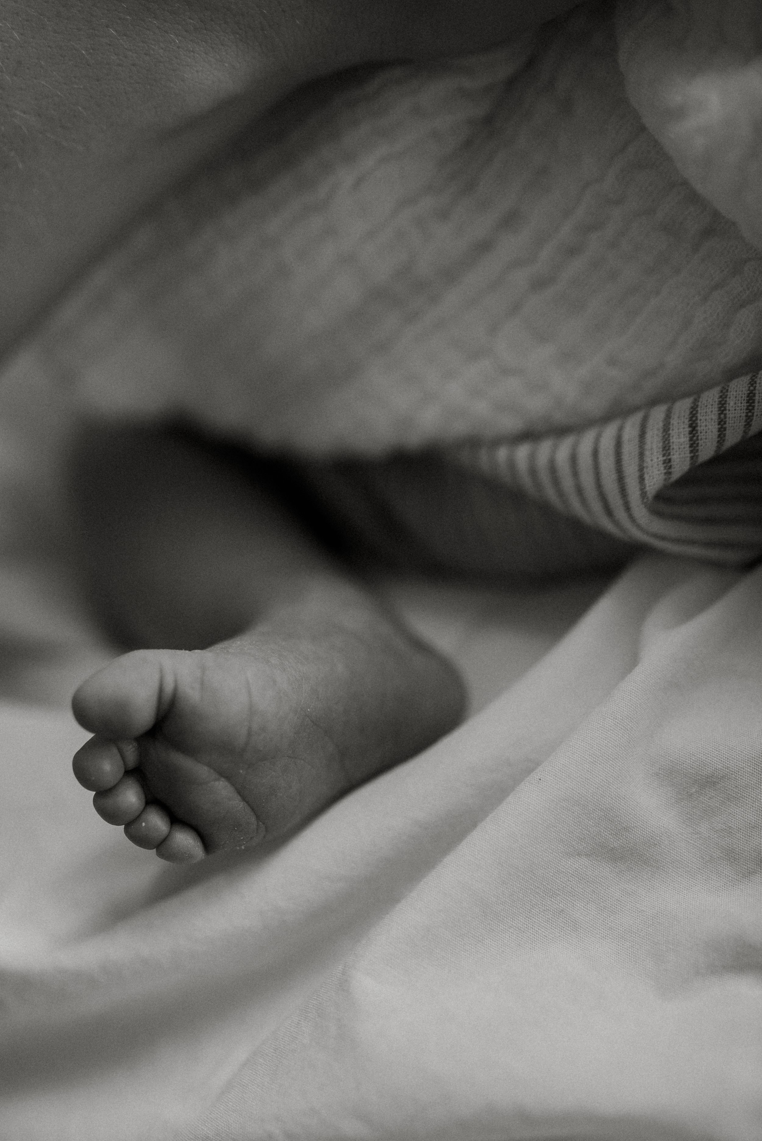 Close-up black and white photograph showing gentle skin textures and shadows.