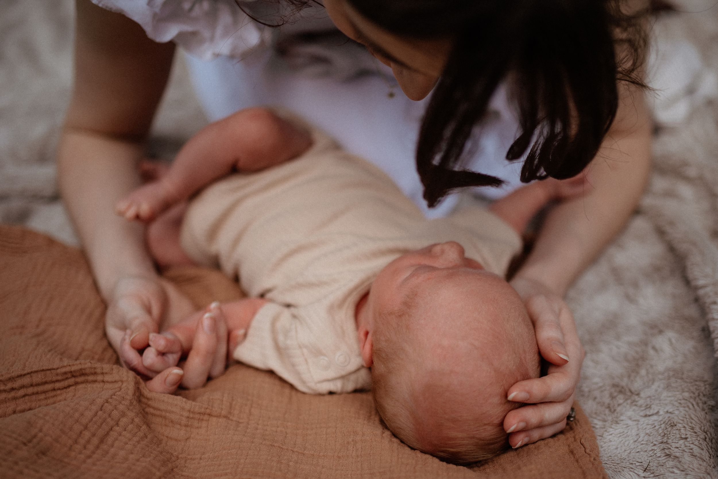 Intimate close-up photograph showing gentle interaction and soft fabric details.
