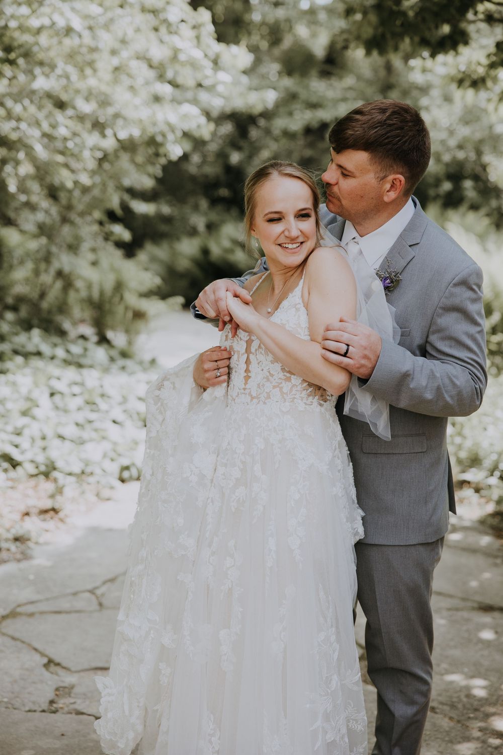 Couple shares joyful moments together in a romantic outdoor wedding photoshoot surrounded by white blossoms.