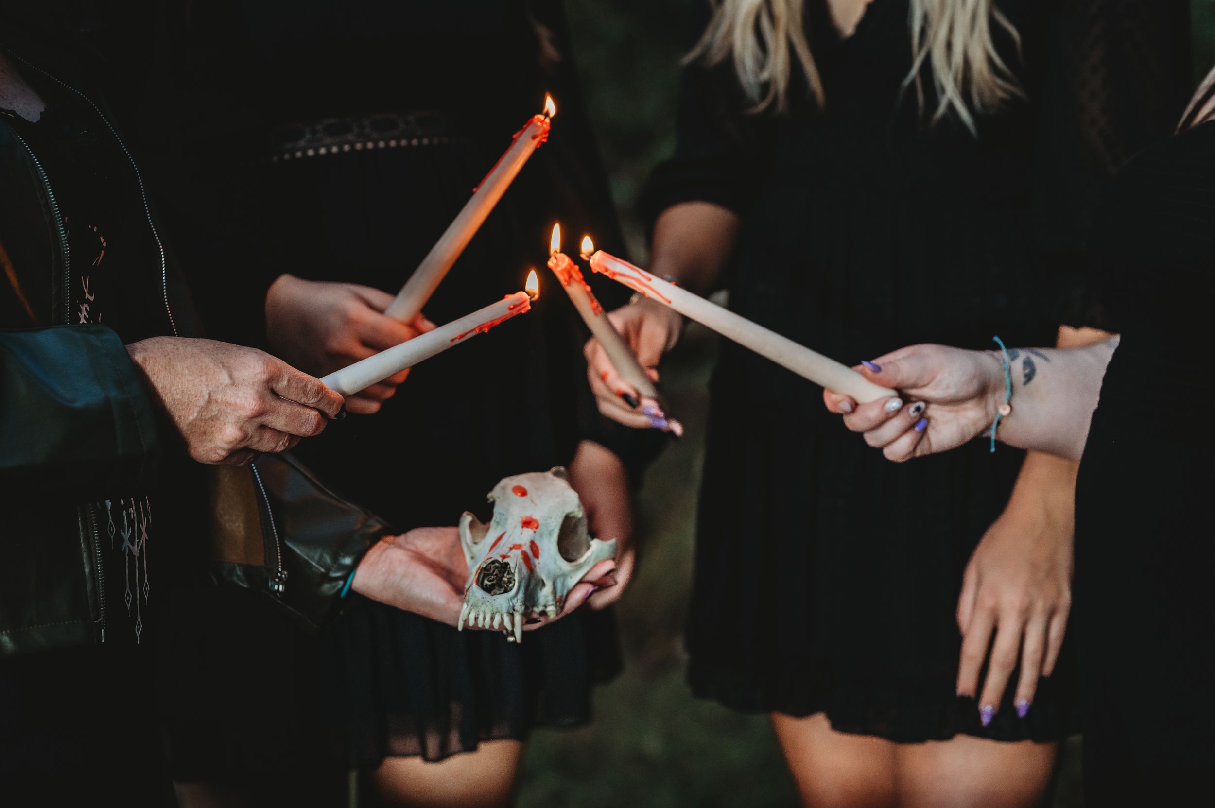 Multiple hands holding knives against dark background in dramatic lighting.