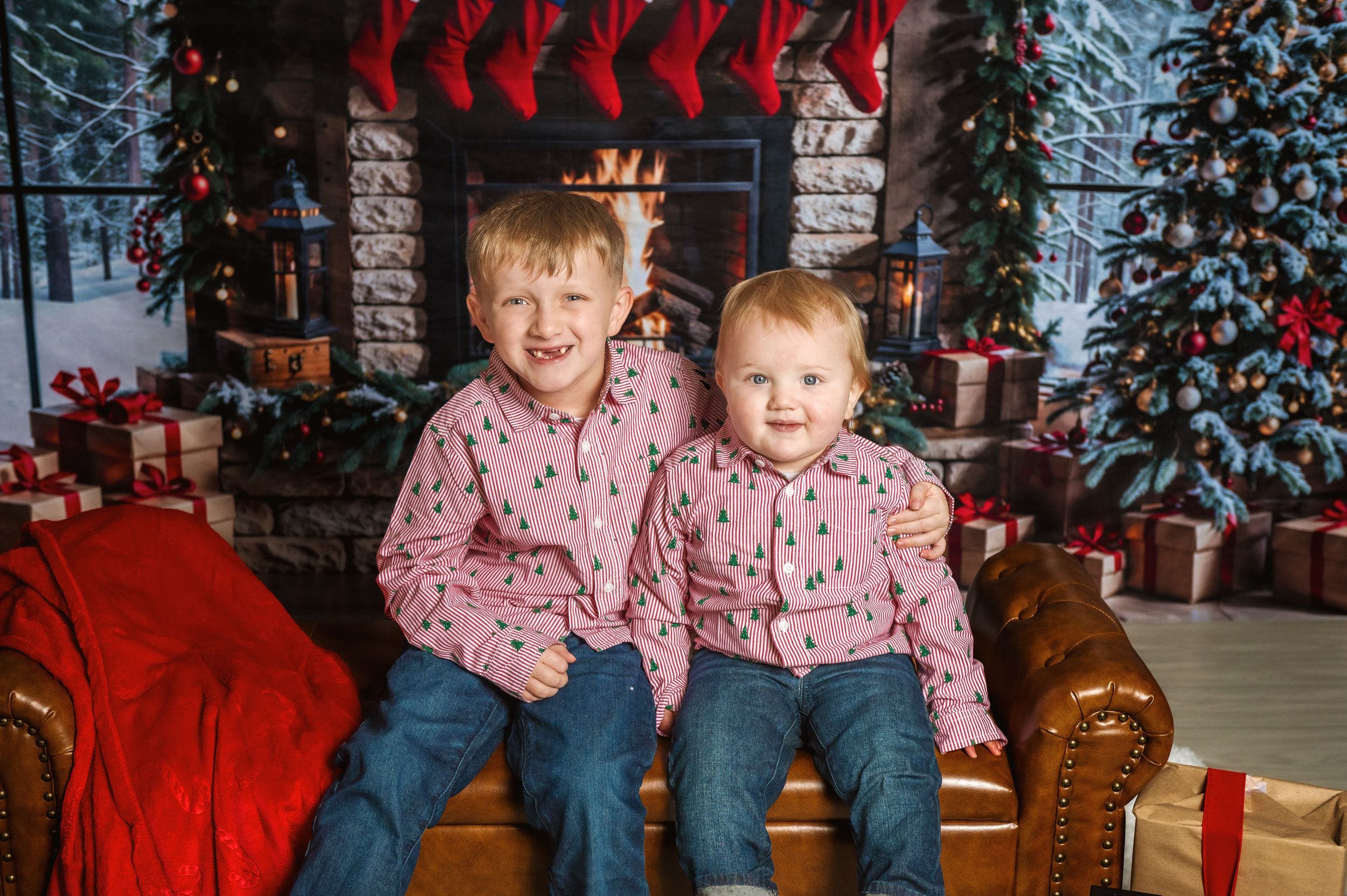 Children pose in front of a decorated Christmas tree and fireplace with wrapped presents.