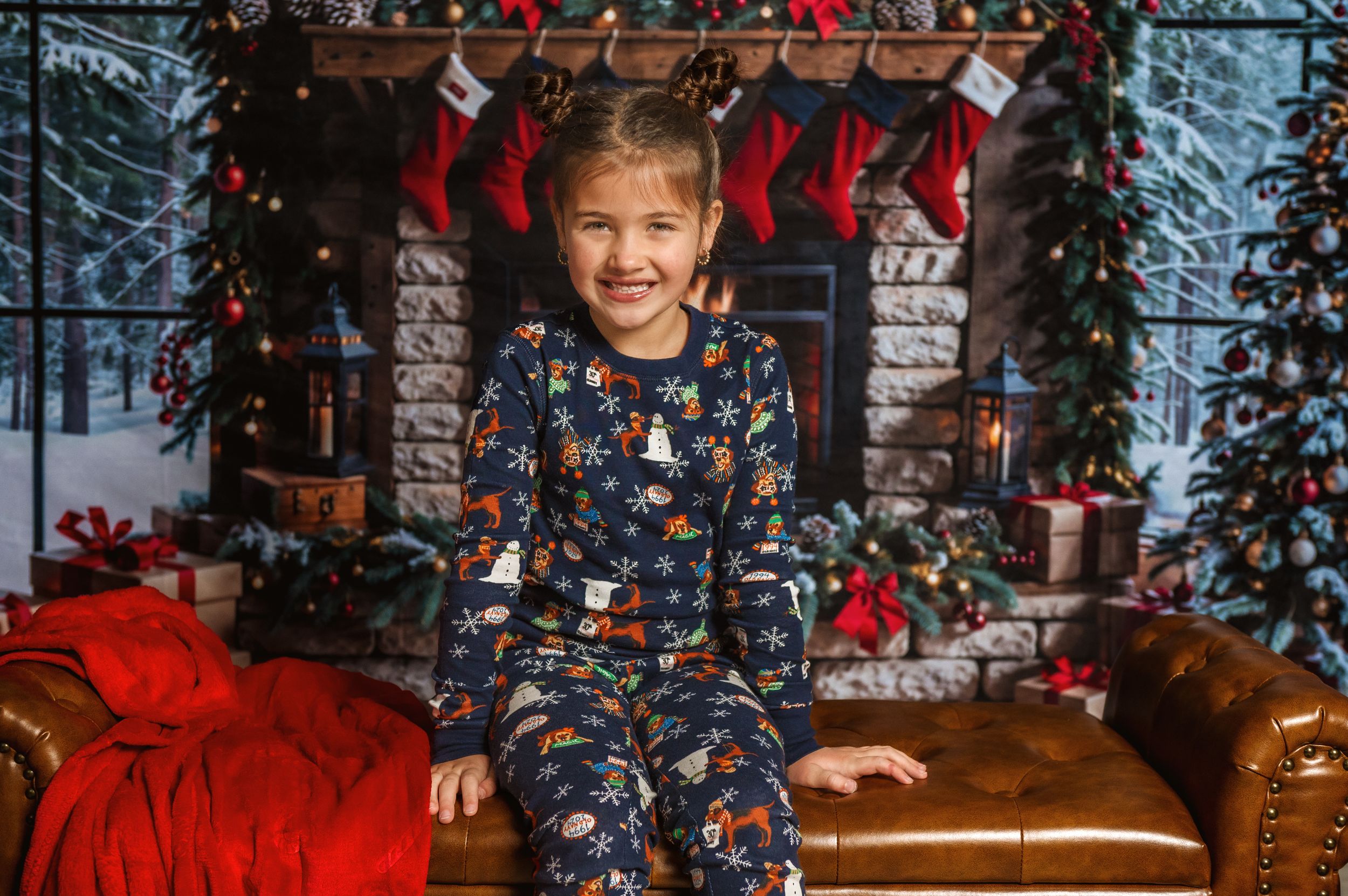 Young person in patterned pajamas sits on brown couch with Christmas decorations.
