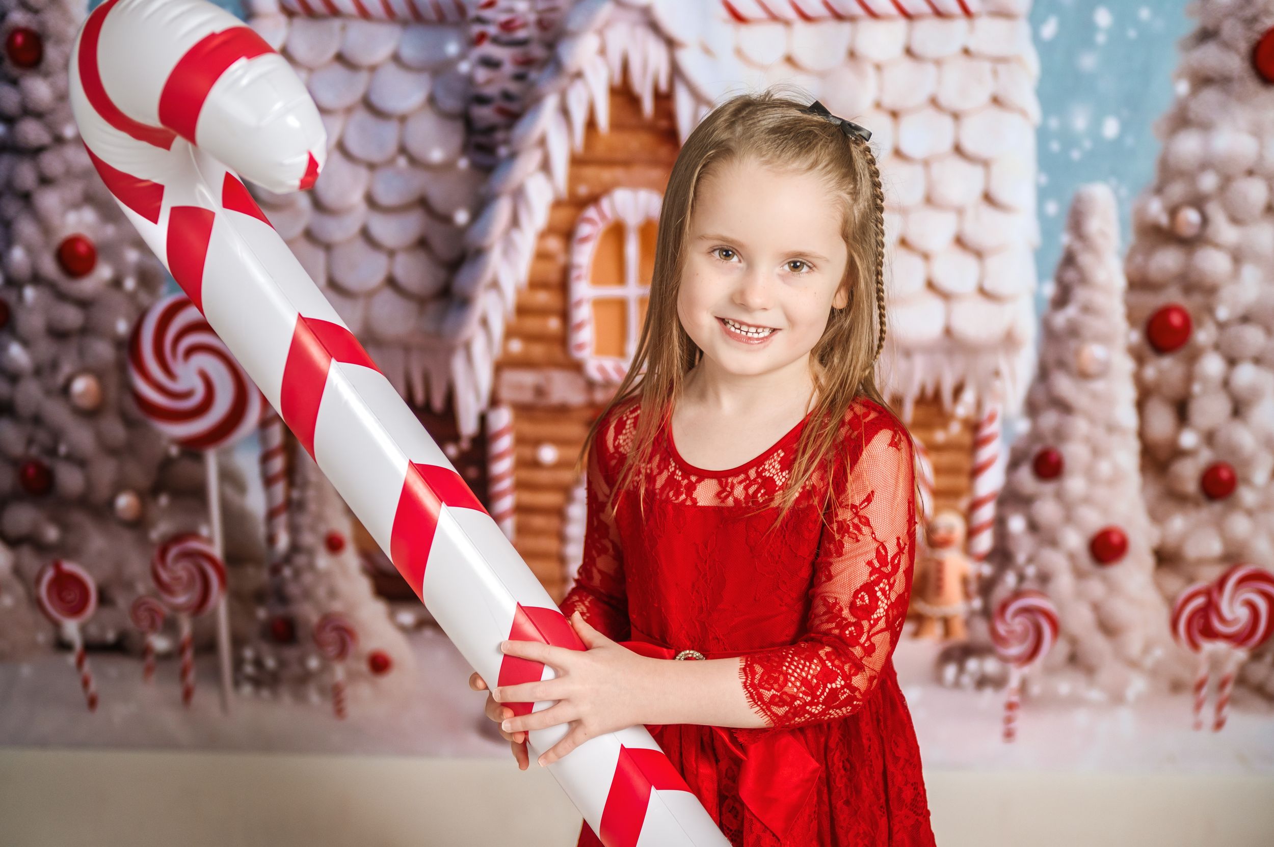 A festive candy cane themed Christmas photo setup with red and white decorations.
