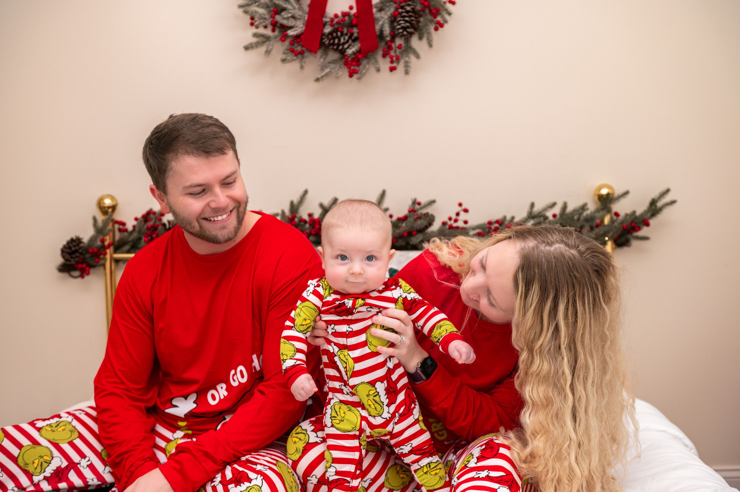 Family wearing striped Christmas pajamas sits together with holiday decorations.
