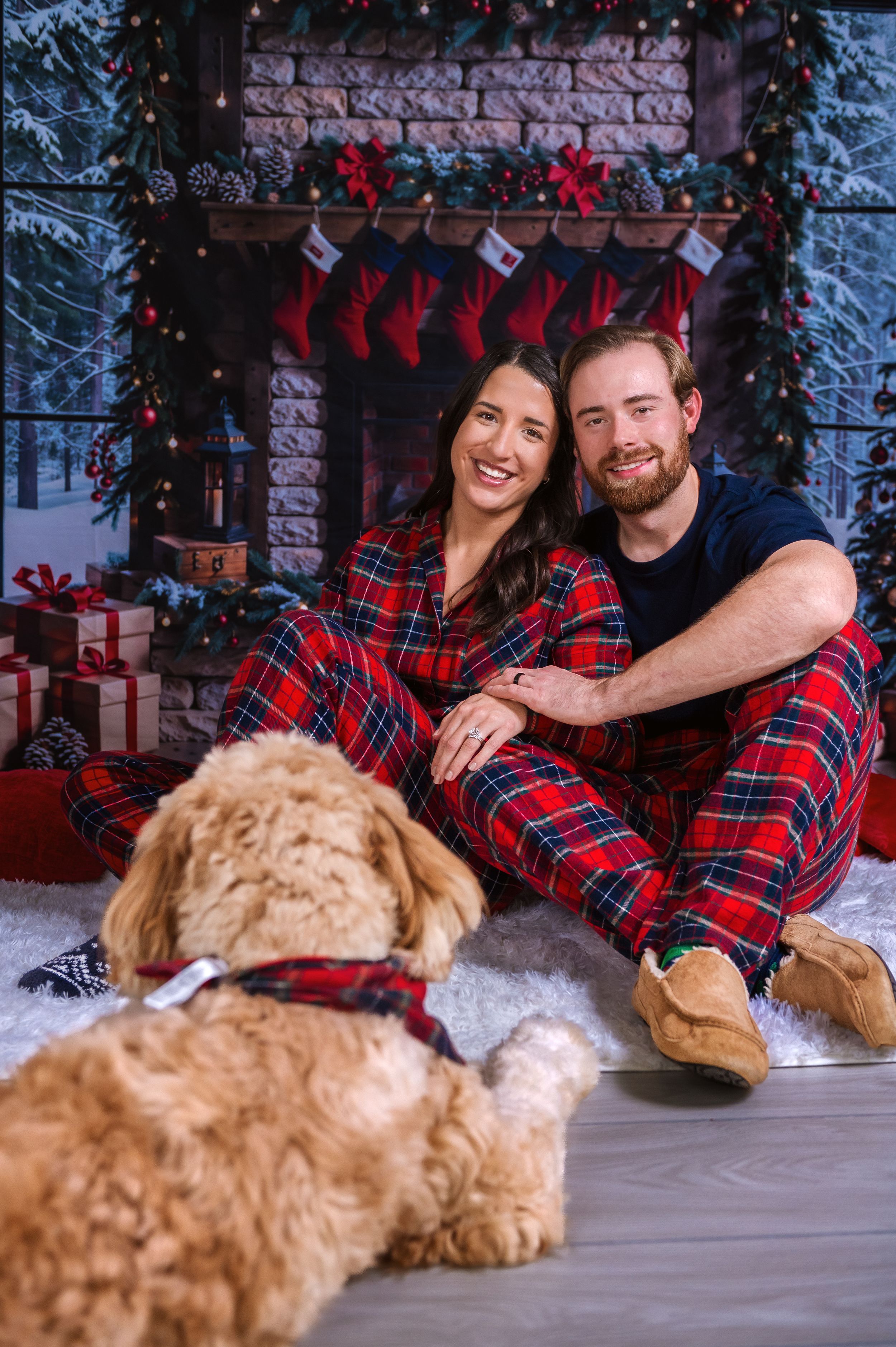 Family holiday photo with goldendoodle dog in front of Christmas backdrop.