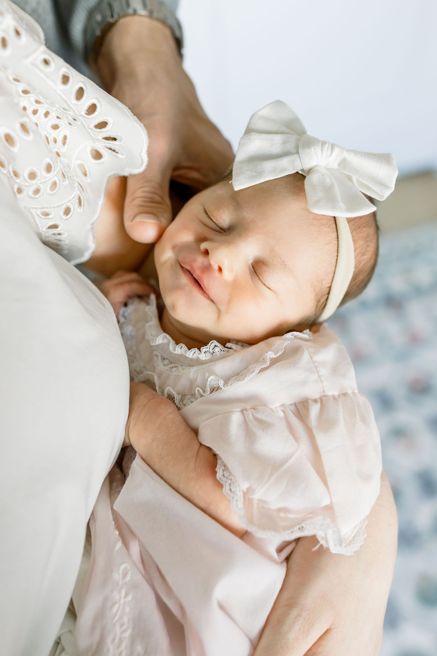 Sleeping baby in white dress with bow headband.