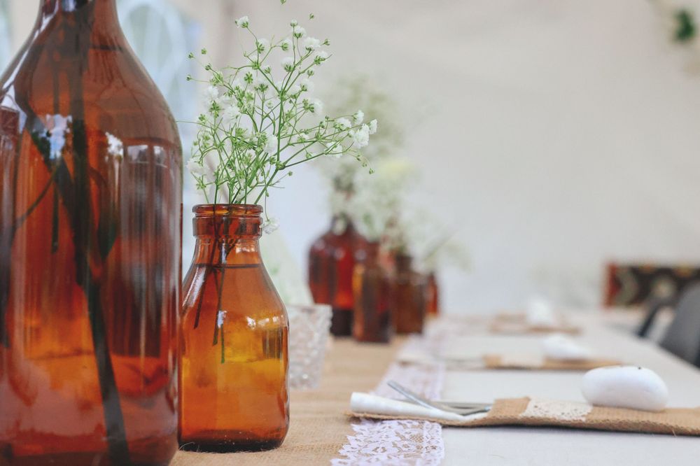 Amber glass bottles with baby's breath flowers on lace tablecloth.