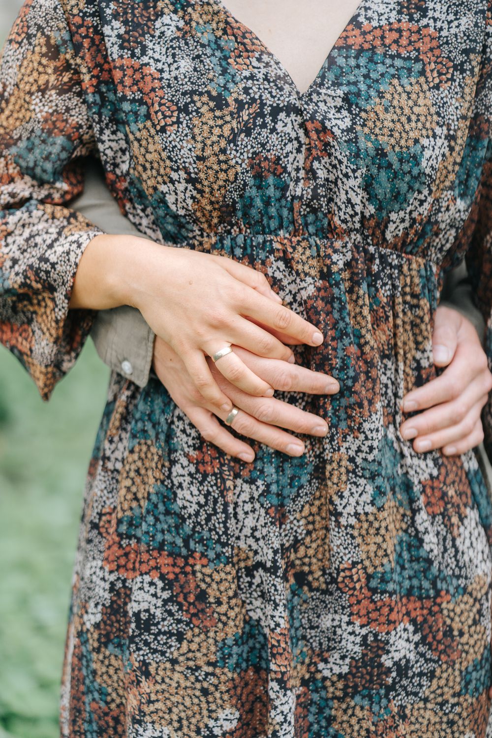 Close-up of hands resting on a patterned dress showing an engagement ring.