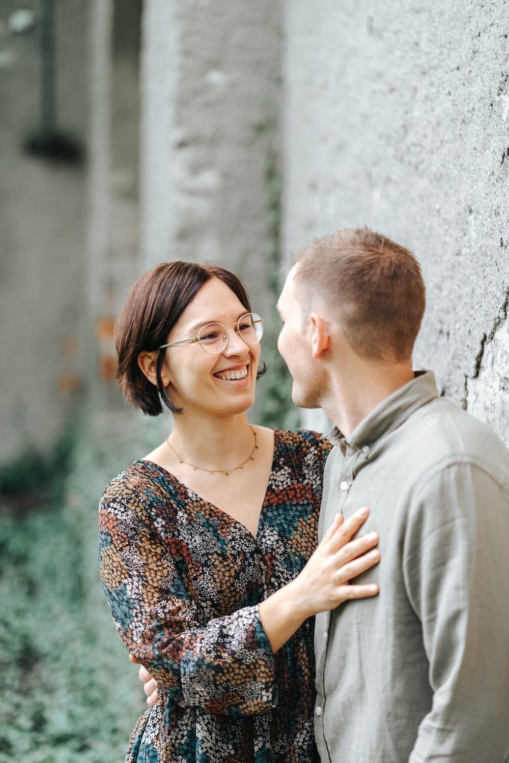 A couple shares a joyful moment together against a white wall backdrop.